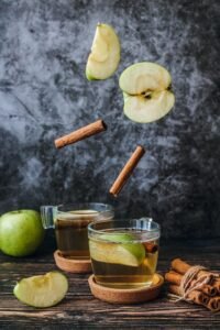 Apple Cider Moscow Mule cocktail. Two glasses with cocktail, apple, cinnamon sticks. 