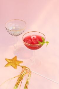Cranberry Vodka Martini cocktail. Red cocktail with ice and empty glass. Pink background and star. 